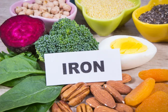 foods-to-avoid-when-you-have-pregnancy-anemia-for-better-iron-absorption A close-up photograph of a table with various iron-rich foods, including almonds, dried apricots, pecans, broccoli, spinach, and a halved hard-boiled egg.